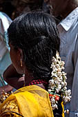 Scented garlands of fresh flowers swaying in women black hair near the Swamimalai temple. 